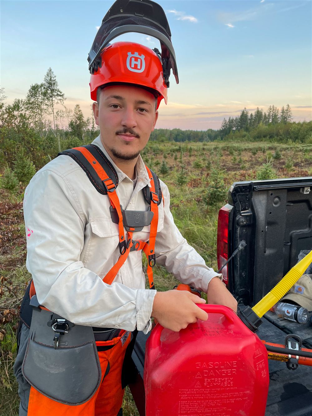 Membre de l'équipe Pro Arbor en équipement de protection complet — casque forestier, harnais et pantalon de sécurité — sur un chantier de plantation.